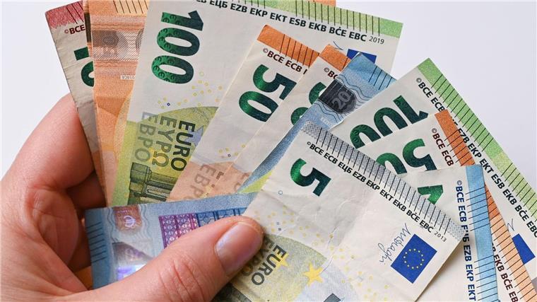 Antrag für schwerbehinderte Arbeitnehmer künftig digital Eine Frau hält Geldscheine in der Hand.