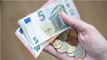 Eine Frau hält Geldscheine und Münzen in der Hand.