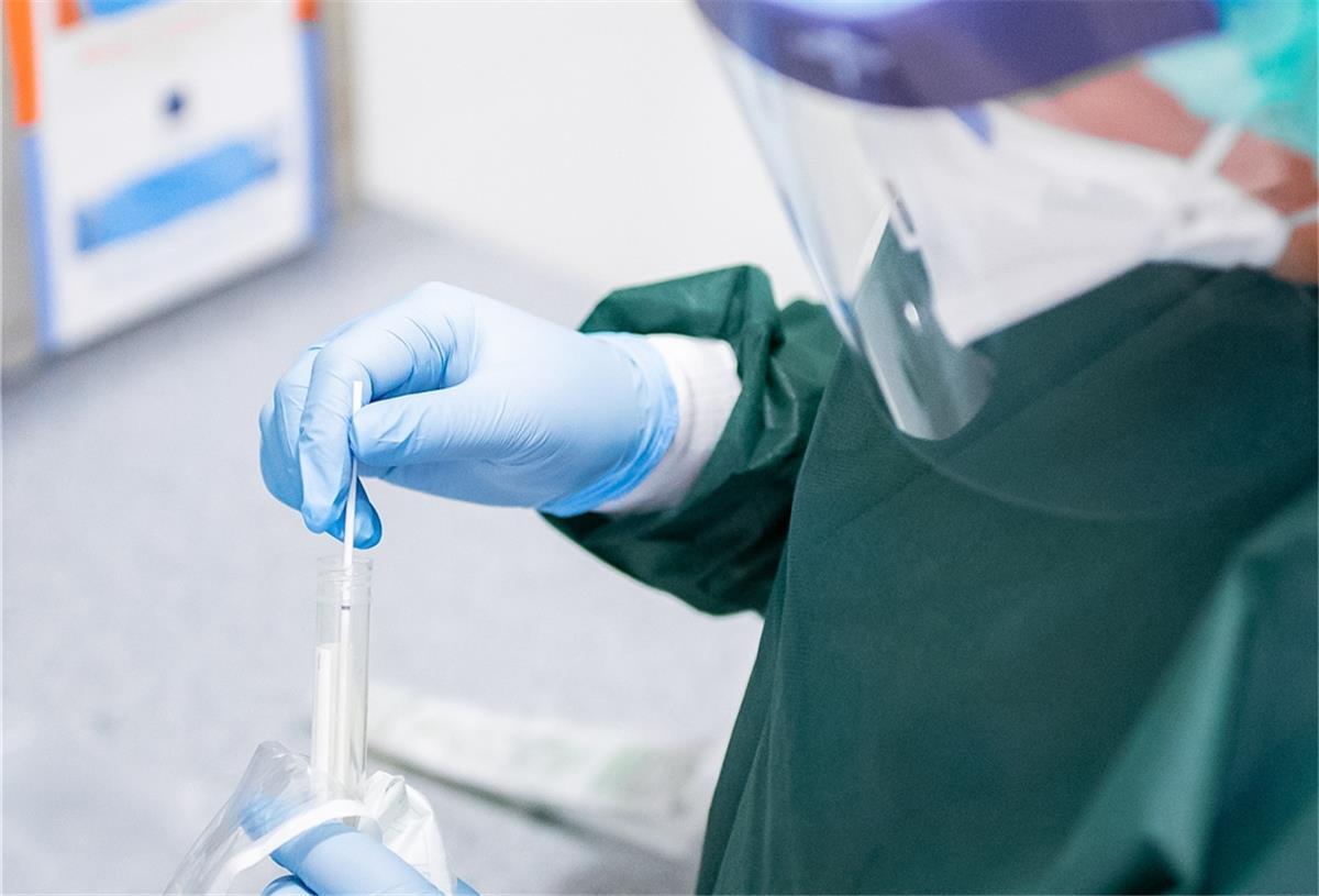 Erster Coronavirusfall im Landkreis Cuxhaven Eine Frau in Schutzkleidung packt ein Abstrichröhrchen aus.