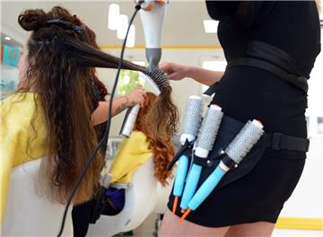 Eine Friseurin föhnt einer Kundin die Haare.