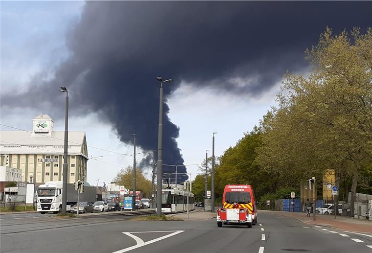 Feuerwehr und Bagger kämpfen weiter gegen Großbrand in Bremen Eine große Rauchsäule ist über Bremen zu sehen, nachdem mehrere Lagerhallen in Brand geraten sind.