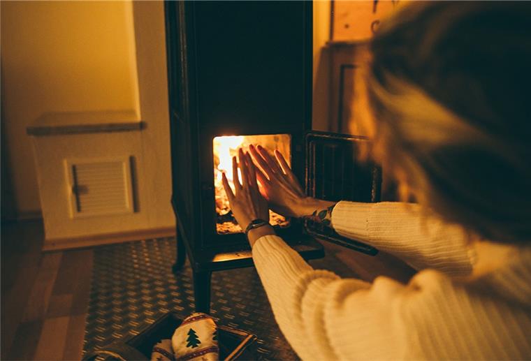 Frau wärmt sich ihre Hände am Kamin