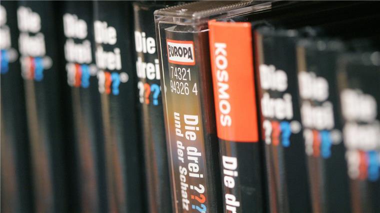 „Die drei ???“: So wurden sie die coolsten Detektive Deutschlands Eine im Hörspiel-Label Europa erschienene Hörspielkassette der Jugend-Krimi-Reihe „Die drei ???“ steht in einer Buchhandlung zwischen Büchern der Reihe aus dem Stuttgarter Jugendbuchverlag Franckh-Kosmos.