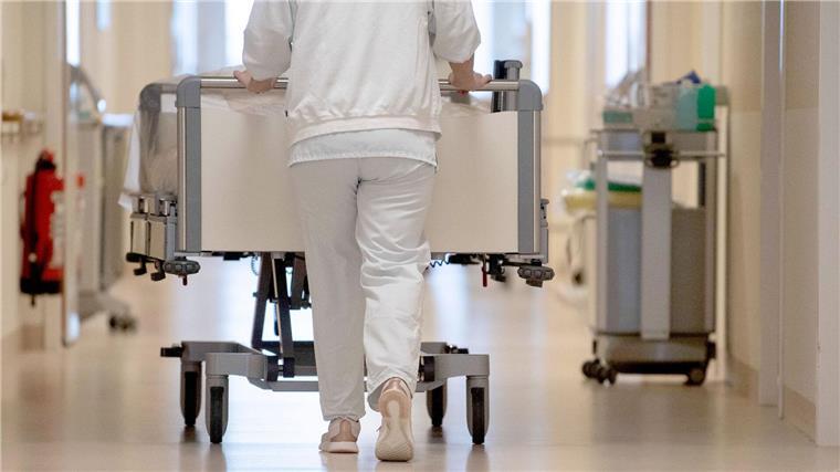 Landtag beschließt millionenteures Krankenhausprogramm Eine Krankenpflegerin schiebt ein Bett durch einen Flur.