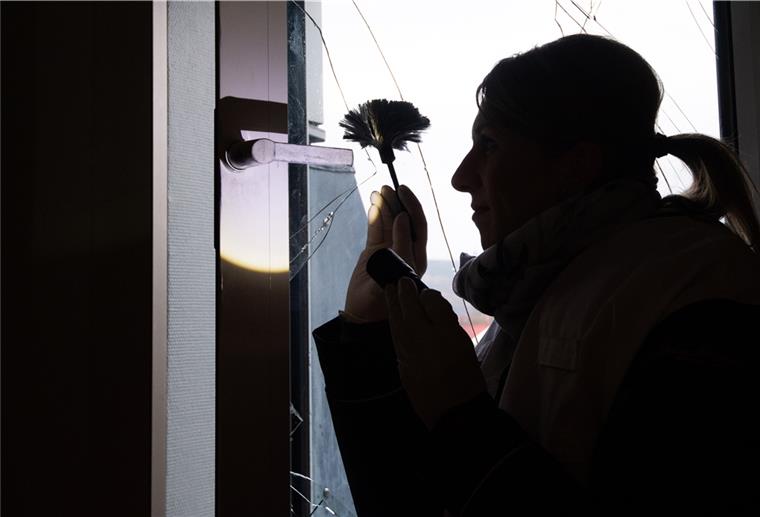 Eine Kriminaloberkommissarin sichert nach einem Einbruch Spuren an einer eingeschlagenen Fensterscheibe.