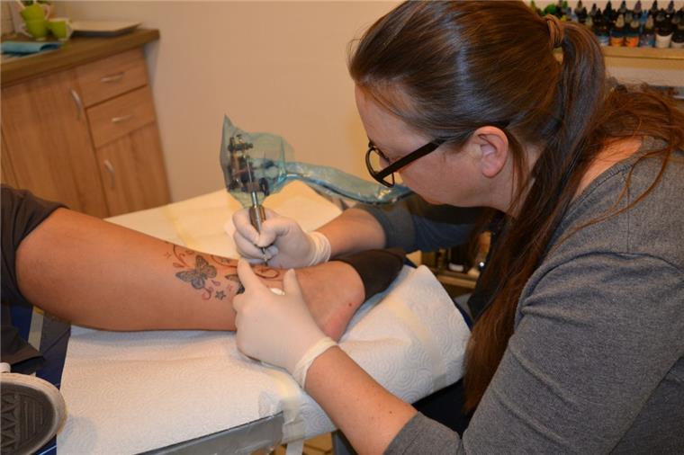 Tattoo-Studio Zeven: Ein Gefühl wie 1000 Nadelstiche Eine Kundin lässt sich ihr Kunstwerk am Bein bestehend aus Schmetterlingen und Sternen von Tätowiererin Anja Czaya aus Zeven mit Schnörkel erweitern.