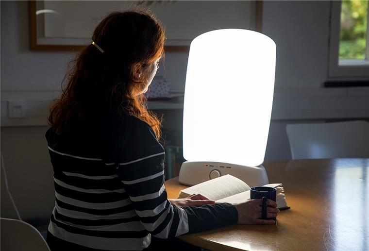 Frau vor Lampe mit Buch