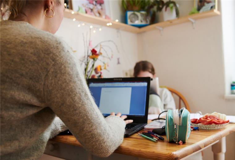 Ohne Homeoffice gibt‘s weniger Bewerber Eine Mutter arbeitet am Küchentisch, während ihre Tochter gegenüber in ein Tablet guckt. Nach Ansicht von Experten sollten Unternehmen darauf achten, dass nicht vor allem Frauen im Homeoffice arbeiten, während Männer im Büro bleiben.