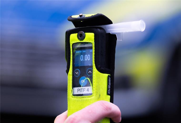 Ein Polizeibeamter hält während einer Verkehrskontrolle ein Messgerät, das den Alkoholwert von Null Promille anzeigt.