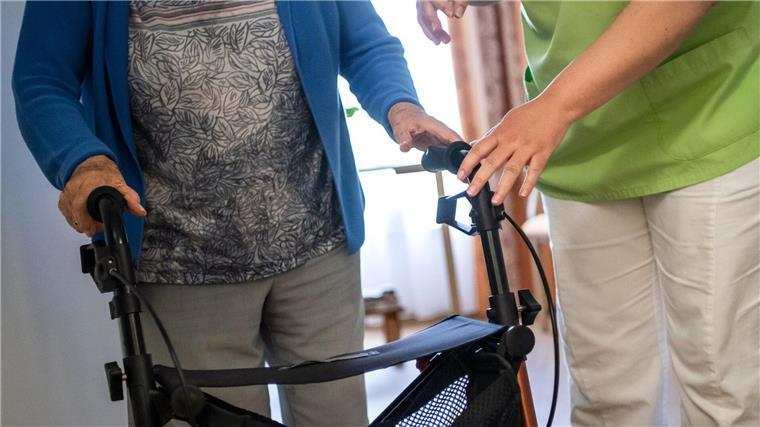 Zuzahlungen für Pflege im Heim deutlich gestiegen Eine Pflegefachkraft hilft einer Bewohnerin in einem Seniorenheim mit ihrem Rollator.