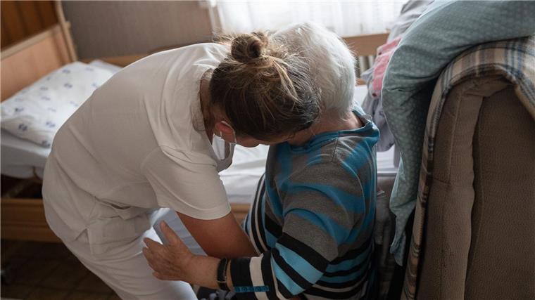 Pflegebranche in Niedersachsen „extrem unter Druck“ Eine Pflegefachkraft hilft in der ambulanten Pflege einer Frau beim Umsetzen.