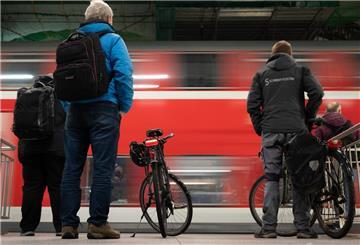 Fahrgäste stehen auf einem Bahnsteig, während eine S-Bahn vorbeifährt