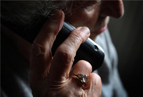 Eine Seniorin mit einem Telefon in der Hand.