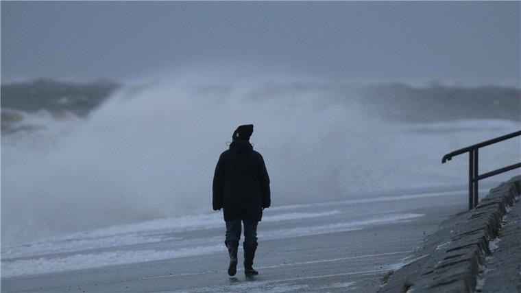 Eine Spaziergängerin läuft bei stürmischem Wetter am Nordstrand der ostfriesischen Insel Norderney.