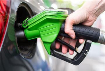 Eine Frau hält an einer Tankstelle an einer Zapfsäule eine Zapfpistole. 