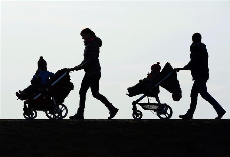 Zwei Mütter schieben Kinderwagen eine Landstraße entlang.