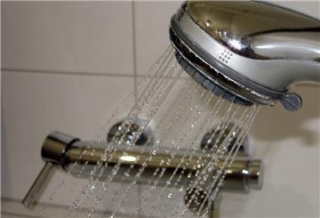 Wasser perlt in einem Badezimmer aus einer Dusche.
