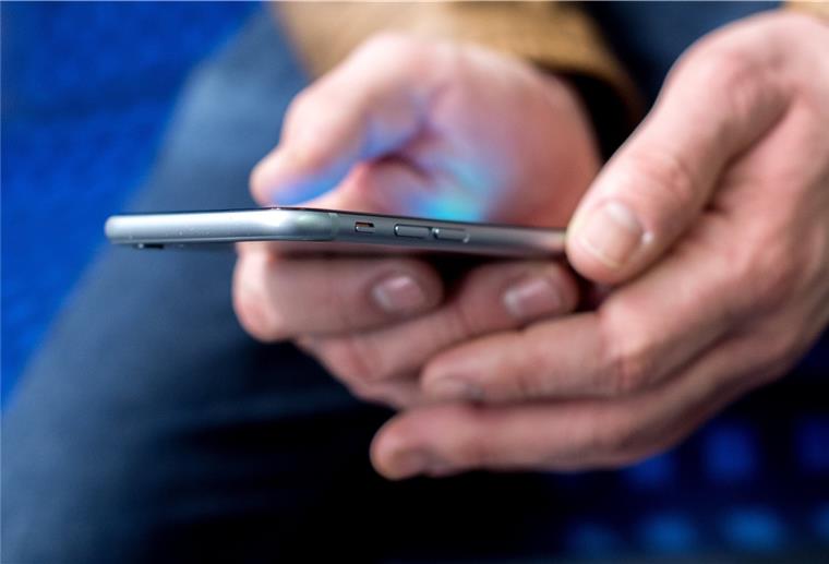 Selbsthilfe: Die Ersten kommen wieder zusammen Ein Mann hält ein Handy in den Händen.