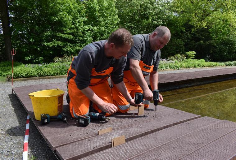 Neue Steganlage in Bad Bederkesa: Worauf sich Besucher schon jetzt freuen können Zwei Männer legen einen neuen Steg am Brunnen in Bad Bederkesa an.