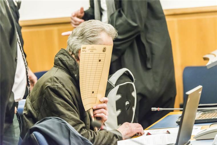 Massenhafter Betrug: Bremerhavener Senior und seine Rentner-Komplizen vor Gericht Einer der fünf Angeklagten hält sich im Gerichtssaal eine Mappe vor das Gesicht, um nicht erkannt zu werden.