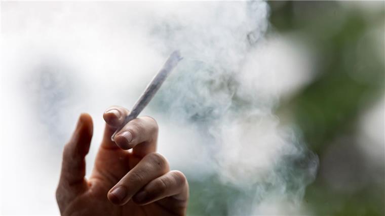 Suchthilfe warnt: Erster Kontakt mit Cannabis oft schon früh Ein Mann hält einen Joint in der Hand.