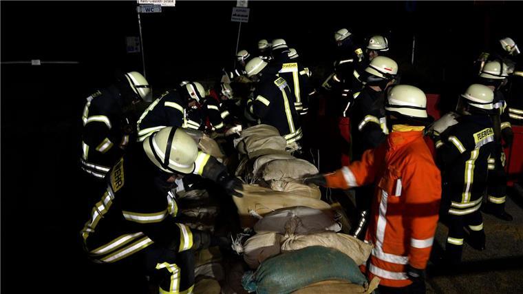 Einsatzkräfte der Feuerwehr sichern eine Deichschart mit Sandsäcken.