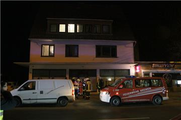 Einsatzkräfte des Rettungsdienstes und der Feuerwehr stehen vor dem Haus in Bremen-Farge, in dem bei einem Grillabend im Keller acht Menschen teils lebensgefährlich verletzt worden sind, 