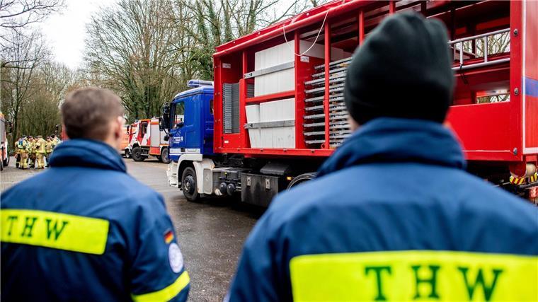 Einsatzkräfte des Technischen Hilfswerks (THW) stehen vor einem LKW.