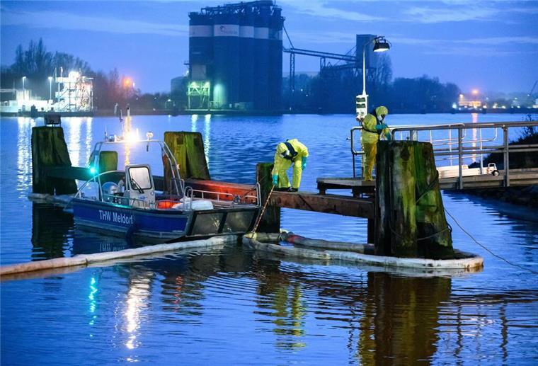 Ausgelaufenes Öl stoppt Schifffahrt auf dem Nord-Ostsee-Kanal Einsatzkräfte des THW in Schutzanzügen arbeiten mit Ölschlengeln an einem Steg.