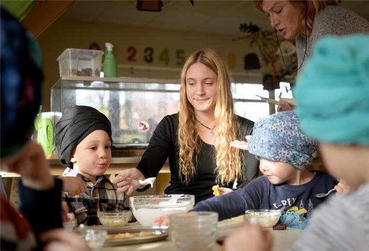 Zwei Frauen beschäftigen Kinder in einem Kindergarten. 