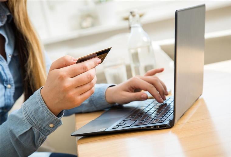 Top-Finanzen, aber kein perfekter Score? Das steckt hinter dem Schufa-System Eine Person sitz am Laptop und hält eine Kreditkarte in der Hand.