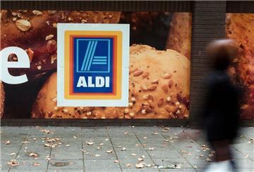 Eine Person läuft an einer Aldi-Filiale vorbei. In einer Filiale in England muss man zahlen, bevor man einkaufen darf.
