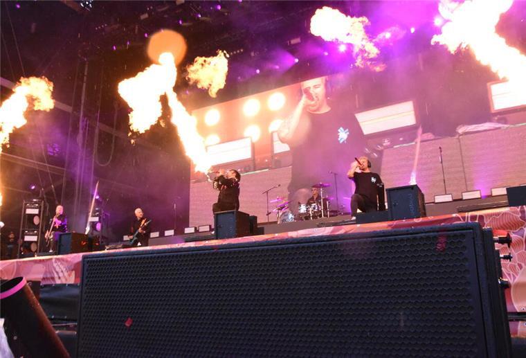 Regen verdunstet in den Deichbrandflammen Schwarz gekleidete Männer auf Bühne mit Pyrotechnik