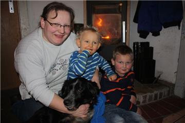 Endlich wieder vereint: Tanja Drechsler mit ihren Söhnen Timo (links) und Christian sowie Familienhund Jasper am warmen Ofen.