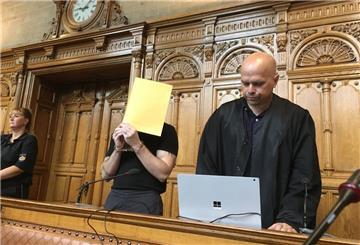 Zwei Männer, einer hält eine Mappe vor das Gesicht