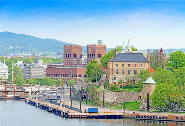 Frühlingserwachen in Oslo erleben: Jetzt traumhafte Mini-Kreuzfahrt buchen Blick auf Oslo vom Wasser aus. Zu sehen ist das Rathaus der norwegischen Hauptstadt und die Festung Akershus.