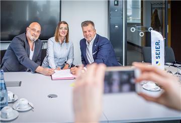 Erinnerungsfoto: Hochschulrektor Prof. Alexis Papathanassis (links) unterzeichnet mit Ulrich Seier die Kooperation. Biljana Scholz wird die erste duale Studentin sein.