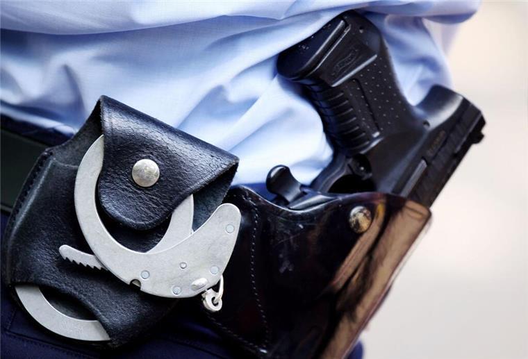 Ein Polizist trägt Handschellen und seine Dienstwaffe am Gürtel.