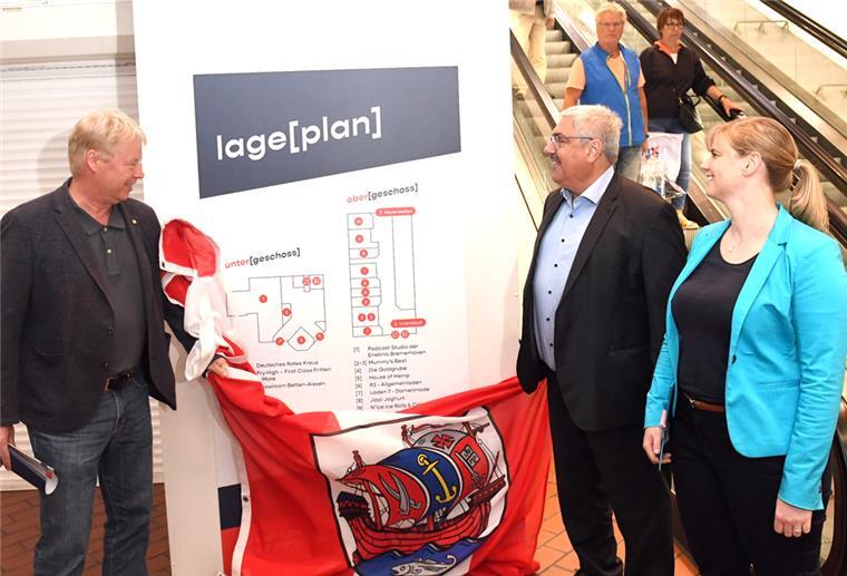 Bremerhaven: Kreative Zwischennutzung bis zum Karstadt-Abriss Eröffnung der zwischengenutzten Hafenpassage an der Rolltreppe zum Ex-Karstadt-Gebäude (von links): Dr. Ralf Meyer (Erlebnis Bremerhaven), Oberbürgermeister Melf Grantz (SPD) und Isabelle Bornemann (Seestadt Immobilien) begutachten den Lageplan.