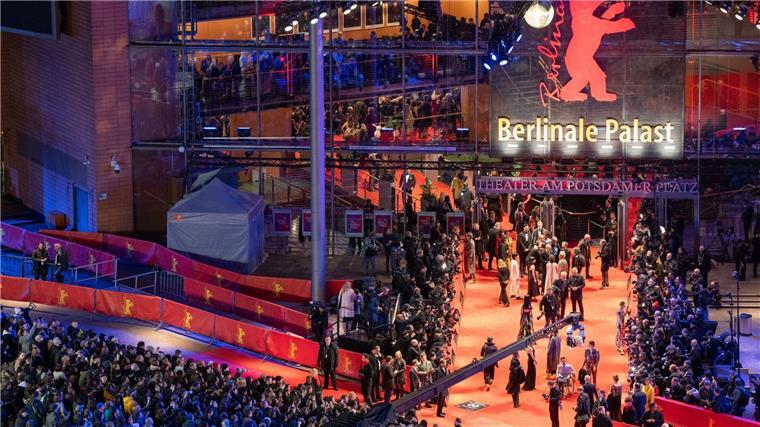 Berlinale gestartet: Prunk und Protest bei Eröffnung Erste Gäste stehen während der Eröffnung der 74. Berlinale auf dem roten Teppich vor dem Berlinale-Palast.