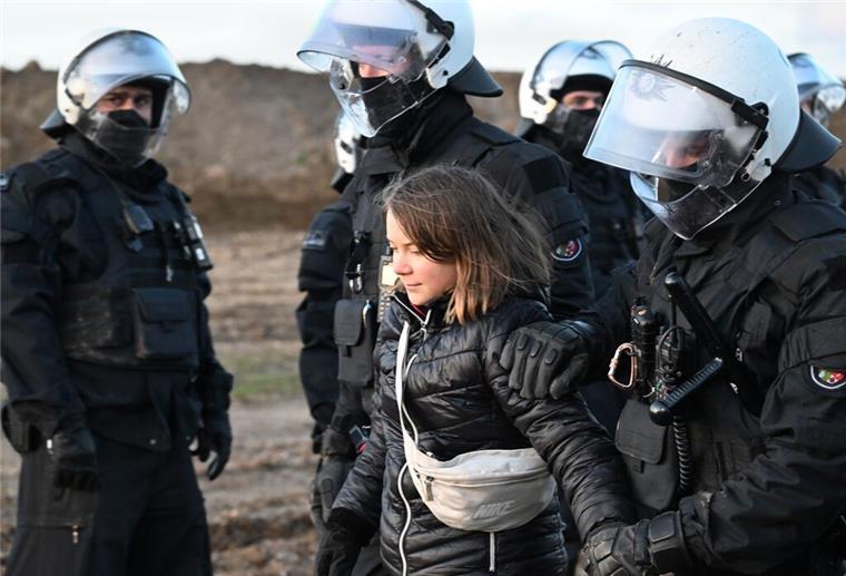 Polizei bestreitet "Inszenierung" mit Greta Thunberg Polizisten führen die schwedische Klimaaktivistin Greta Thunberg (M) aus einer Gruppe von Demonstranten und Aktivisten heraus und vom Rand des Braunkohlentagebaus Garzweiler II weg.