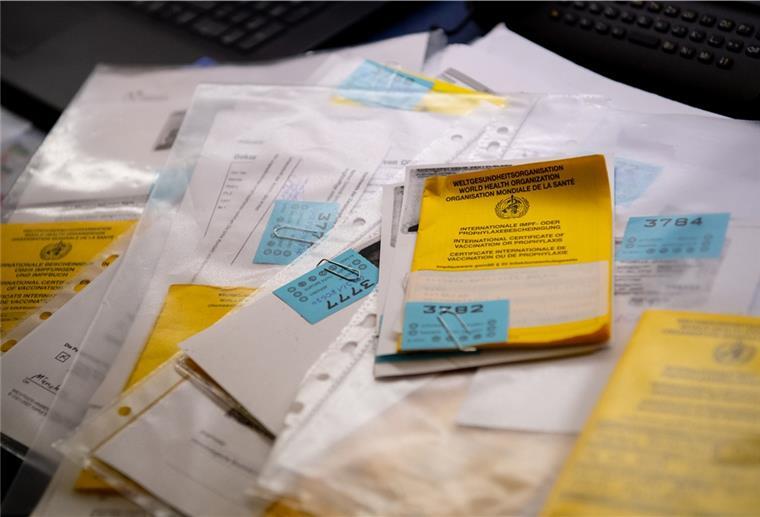Corona: Immer mehr Verfahren zu gefälschten Impfpässen Zahlreiche Impfpässe liegen in einer Apotheke in einem Büro auf einem Tisch.