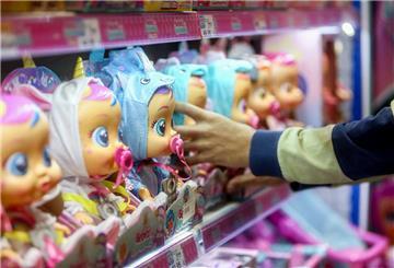 Der Mitarbeiter eines Spielzeugladens stellt Puppen in ein Regal.