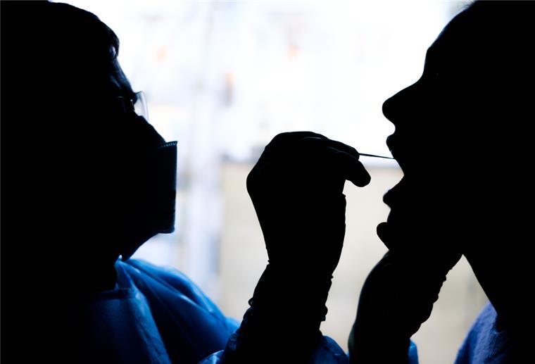  Ein Facharzt für Allgemeinmedizin nimmt bei einer Patientin einen Rachenabstrich