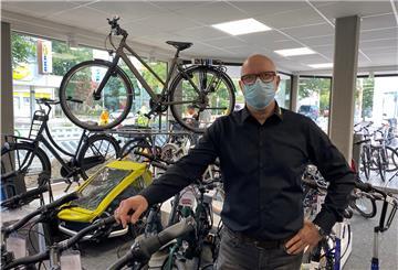 Ein Fahrradhändler vor seinen Fahrrädern.