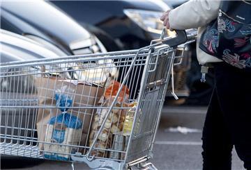 Eine Frau verlässt einen Supermarkt in Madrid mit einem Einkaufswagen.