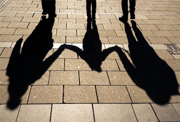 Bis zu 297 Euro monatlich pro Kind! Diese Familien haben Anspruch auf den Kinderzuschlag Die Schatten von zwei Erwachsenen und einem Kind fallen in den Morgenstunden auf den Asphalt.