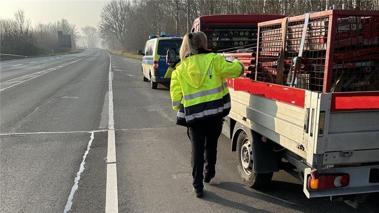 Großkontrolle im Güterverkehr: Polizei deckt zahlreiche Verstöße auf Eine Polizistin kontrolliert ein Fahrzeug während einer Verkehrskontrolle.