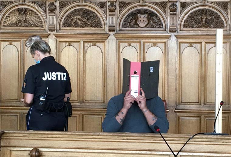 Mordprozess: Angeklagter hatte Wahnvorstellungen Der Angeklagte hält sich einen Ordner vor das Gesicht.