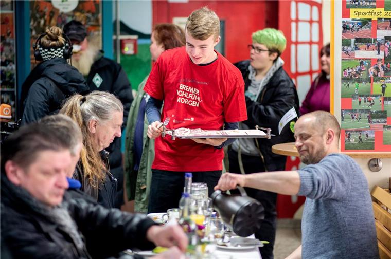 Bremen: Aktionsbündnis schenkt Obdachlosen einen besonderen Vormittag Felix Ellerhorst, freiwilliger Helfer, verteilt während des Frühstücks im Rahmen des Bremer "Wohlfühlmorgens" in der St.-Johannis-Schule Aufschnitt an die Gäste.